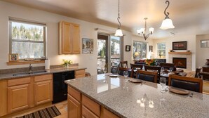 A kitchen with granite countertops, wooden cabinets, and a dining area with a fireplace.