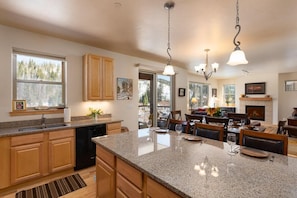 A kitchen with granite countertops, wooden cabinets, and a dining area with a fireplace.