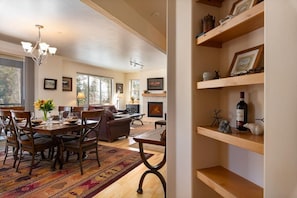 A spacious living area with a fireplace, wooden furniture, and a dining table set for six.