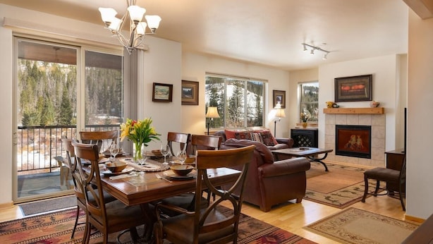 A spacious living area with a dining table, chairs, a sofa, and a fireplace.