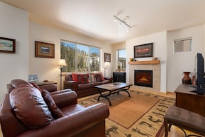 A living room with a fireplace, leather sofa, and a coffee table.