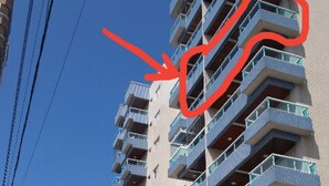 A multi-story residential building with balconies, a gated entrance, and a clear sky. - "Foot in the sand", large balcony, sea view, Wi-Fi, up to 6 people, no pool (Guilhermina)