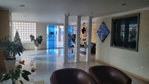 A spacious lobby with a tiled floor, a large window with decorative glass, and several potted plants. - "Foot in the sand", large balcony, sea view, Wi-Fi, up to 6 people, no pool (Guilhermina)