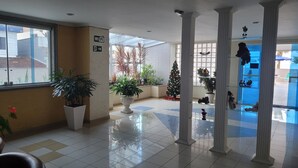 A lobby with tiled floors, potted plants, a Christmas tree, and a Wi-Fi sign. - "Foot in the sand", large balcony, sea view, Wi-Fi, up to 6 people, no pool (Guilhermina)