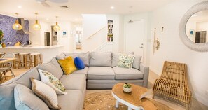 Relax in this stylish living space with a large L-shaped sofa, round coffee table, and wicker chair.