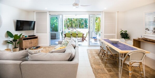 Relax in this inviting living area with a sofa set, dining table, and flat-screen TV, offering a view of the outdoors.