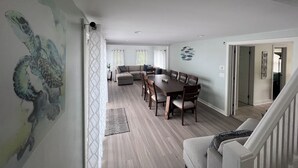 A dining area with a wooden table and chairs, a sofa, and a wall mural.