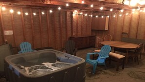 A hot tub in a rustic room with wooden walls, a wooden table, and blue chairs.