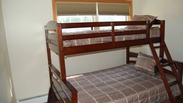 A bunk bed with a wooden frame, a window with blinds, and a checkered bedspread.