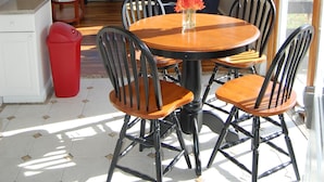 A dining area with a round wooden table, black chairs, and a vase with flowers.