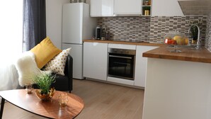 Una cocina moderna con armarios blancos, encimera de madera y horno integrado.