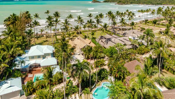 A resort with a pool, palm trees, and a view of the ocean.