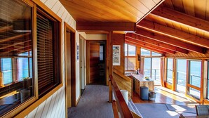 L’intérieur d’une cabane est aménagé avec du bois, de grandes fenêtres, un banc et un coin cuisine.