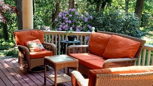 A wooden deck with wicker furniture, including a sofa and chairs, and a small table with a potted plant. - Harvard House--Make Your 2026 Family Gathering An Unforgettable Experience (Waltham)