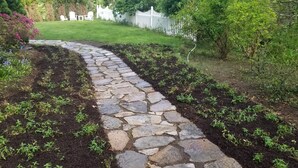 A stone pathway leading through a garden with small plants and a white fence in the background. - Harvard House--Make Your 2026 Family Gathering An Unforgettable Experience (Waltham)