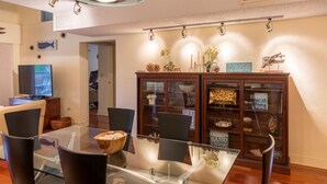 Un espace repas moderne avec une table en verre, des chaises noires et un buffet en bois doté de portes en verre.