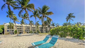Une plage avec des chaises longues et des palmiers.