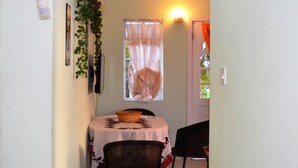 Ein Essbereich mit einem runden Tisch, zwei Stühlen, einem Korb und einem Fenster mit Vorhang.