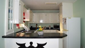 Eine Küche mit weißen Schränken, einer schwarzen Arbeitsplatte, einer Mikrowelle und einem Kühlschrank.
