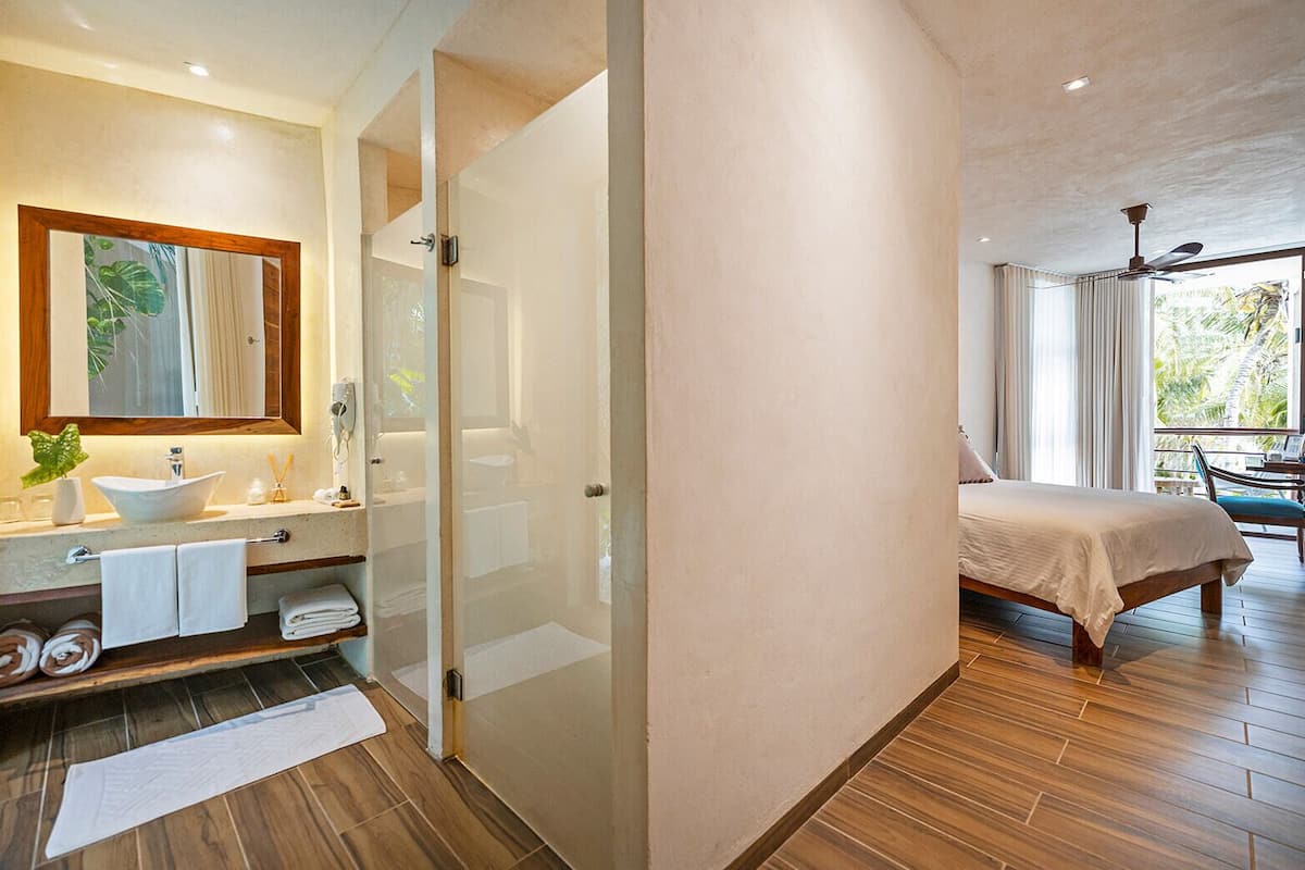 Un baño moderno con un espejo grande, un lavabo sobre encimera y una ducha con mampara de vidrio.
