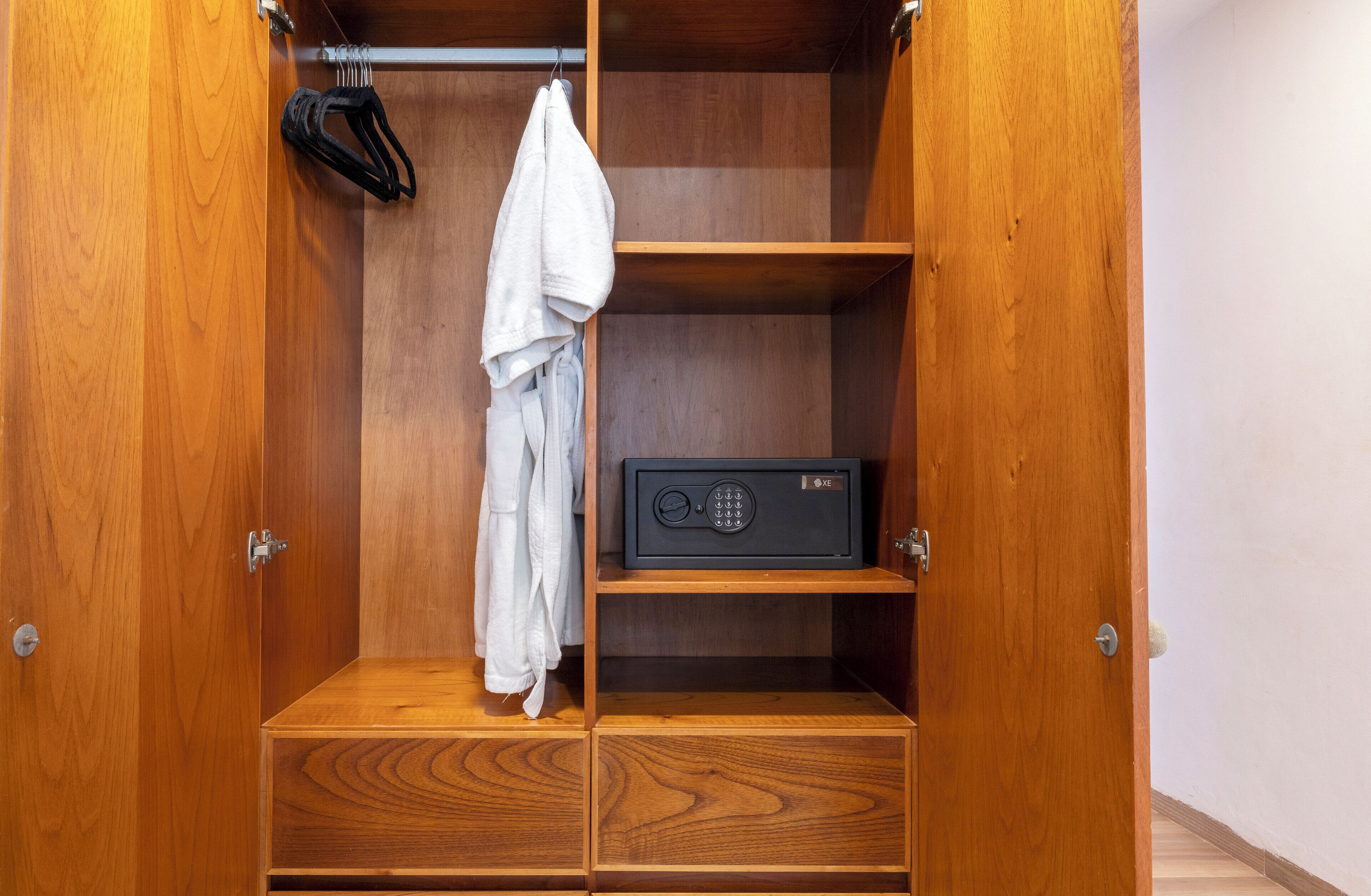 A wooden wardrobe with multiple shelves and drawers, a hanging rack, and a radio on one of the shelves.