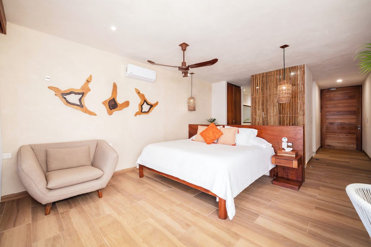 Un dormitorio con cama, una silla, ventilador de techo y decoración en la pared.