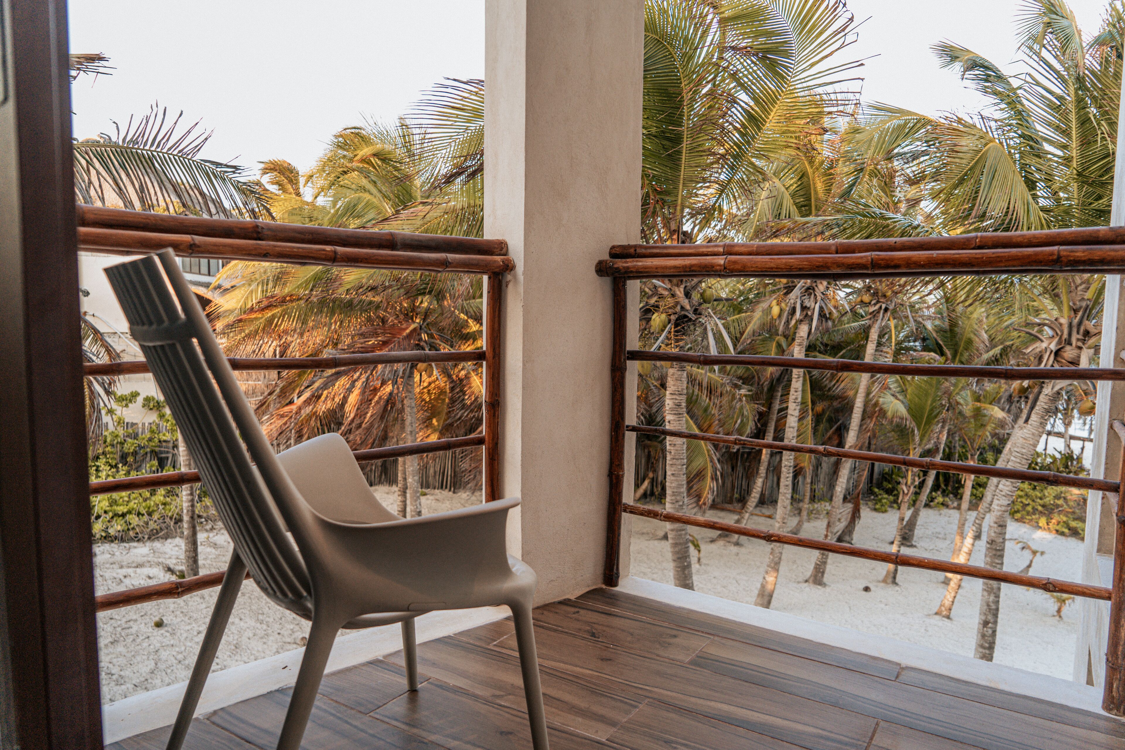 A balcony with a wooden floor, a metal railing, and a plastic chair.