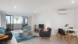 Een moderne woonkamer met een bank, een salontafel en een eethoek met een tafel en stoelen.