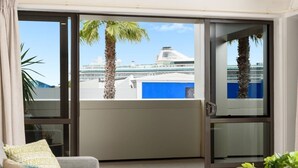 Een balkon met uitzicht op een cruiseschip en palmbomen.