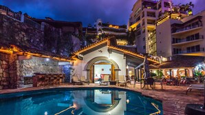 Zona de piscina con muro de piedra y bar con asientos al aire libre.