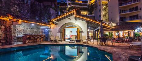 A pool area with a stone wall and a bar with outdoor seating.