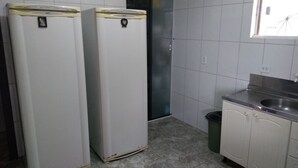 Una cocina con dos refrigeradores blancos, un fregadero y paredes con azulejos.
