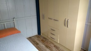 Un dormitorio con cama, armario y una mesita.