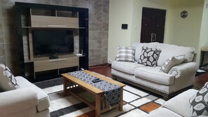 Ein Wohnzimmer mit Flachbildfernseher, einer Couch und einem Couchtisch.