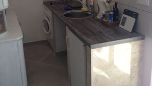 Una cuina petita amb un rentavaixelles integrat, una rentadora i un frigorífic de mida reduïda.