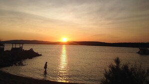 Un capvespre sobre un llac tranquil amb una persona de peu a l'aigua.