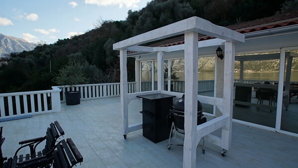 A covered outdoor area with a grill, benches, and a trash bin.