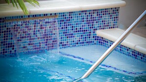 Een zwembad met betegelde rand en een metalen trap.