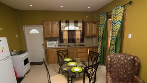 Een kleine keuken met een eettafel, stoelen, een koelkast, een fornuis en een magnetron.