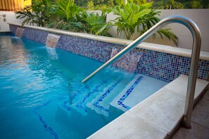 Ein Schwimmbecken mit einer Metallleiter und blau gefliestem Rand.