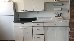 A kitchen with white cabinets, a black countertop, and a sink.