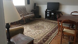 A cozy living room with a wooden coffee table, a patterned rug, a rocking chair, and a television on a stand.