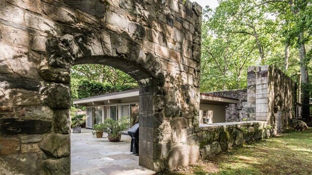 A stone archway leading to a building with a covered patio area.