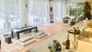 A modern living room with a sofa set, a dining area, and a kitchen with a sink and wine glass.