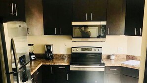 A modern kitchen with dark cabinets, stainless steel appliances, and a granite countertop. - BEAUTIFUL CONDO IN ROSARITO (VILLA SERENA) (Predios Urbanos)