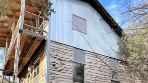 A two-story building with a wooden staircase leading to the upper level. - The Cedar House at Hamilton Creek (Burnet County)