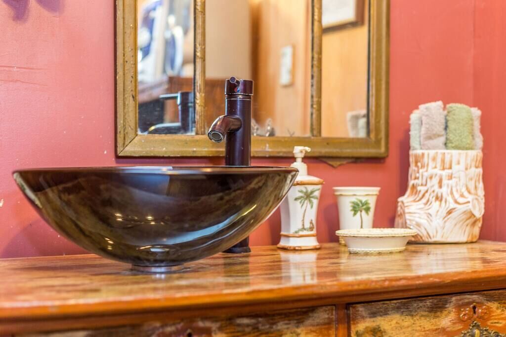 A bathroom sink with a large, dark bowl, a modern faucet, and a mirror above it.