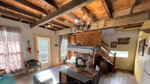 A cozy cabin interior with a dining area, a bunk bed, and a kitchen. - The Cedar House at Hamilton Creek (Burnet County)