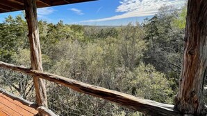 A wooden deck with a view of a forested landscape. - The Cedar House at Hamilton Creek (Burnet County)