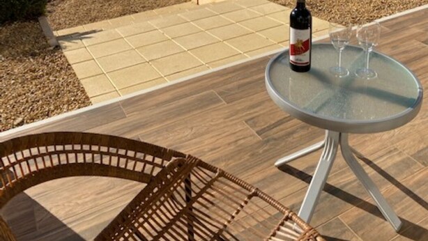 Een terras met een tafel, een fles wijn en twee glazen.